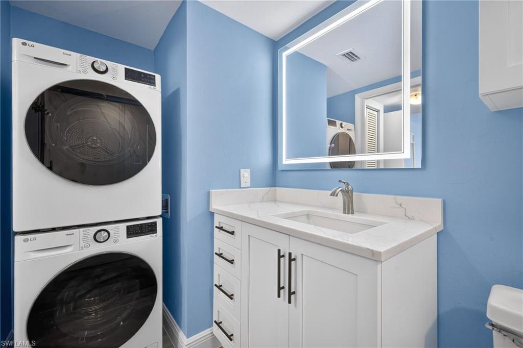 Laundry area featuring stacked washing machine and dryer and a sink