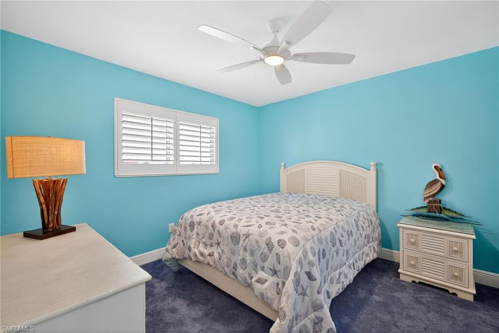 Bedroom with dark colored carpet and a ceiling fan
