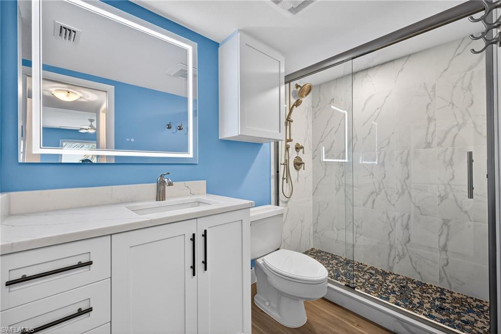Full bathroom with a marble finish shower, vanity, and wood finished floors