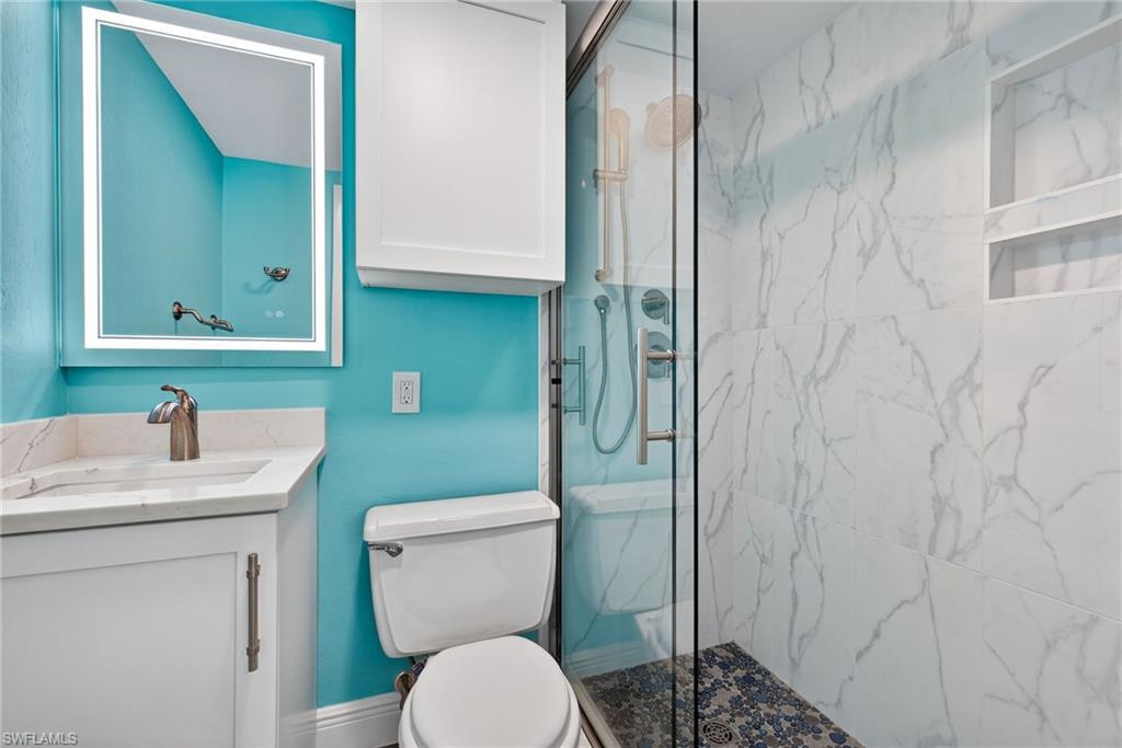 Bathroom featuring vanity and a marble finish shower