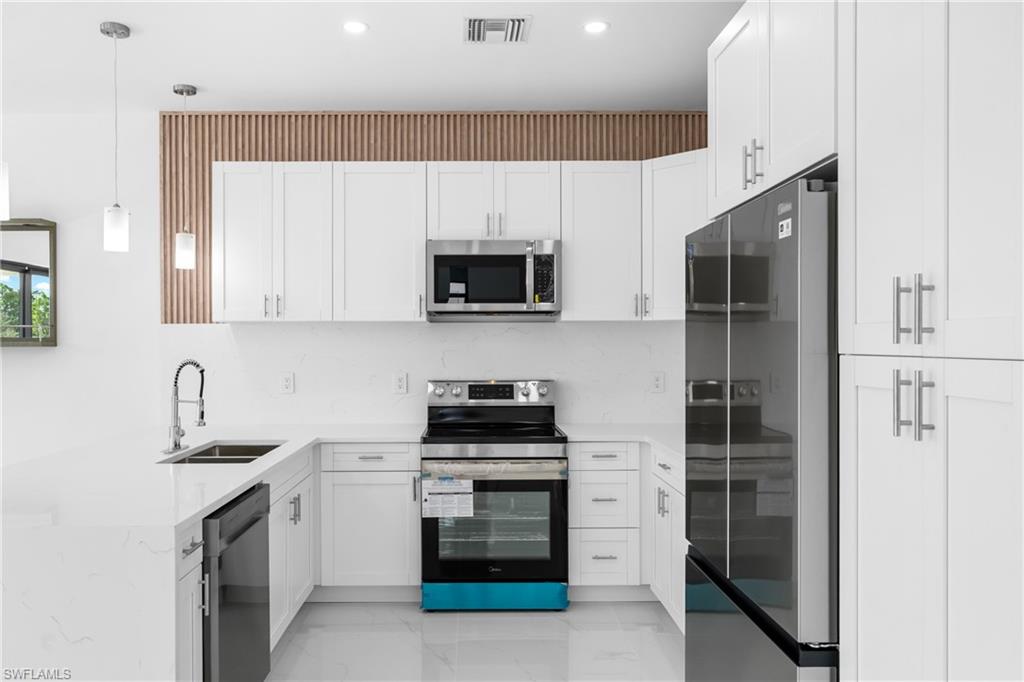 Kitchen featuring white cabinets, a peninsula, and light stone countertops