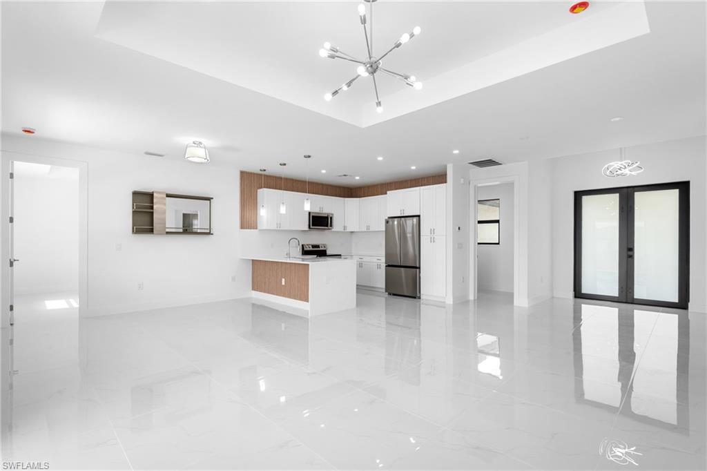 Kitchen with a chandelier, open floor plan, stainless steel appliances, white cabinets, and a peninsula