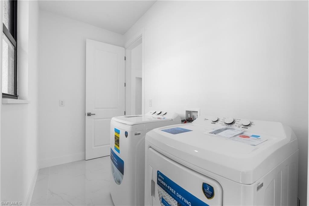 Laundry area with washer and dryer and light marble finish floors