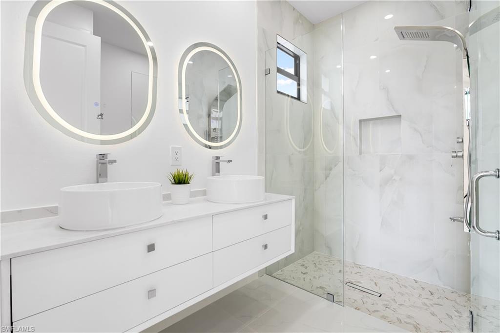 Bathroom with double vanity and a marble finish shower
