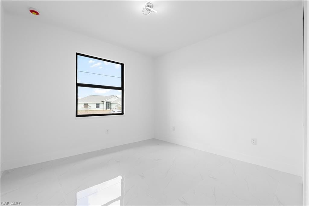 Spare room featuring light marble finish flooring and baseboards