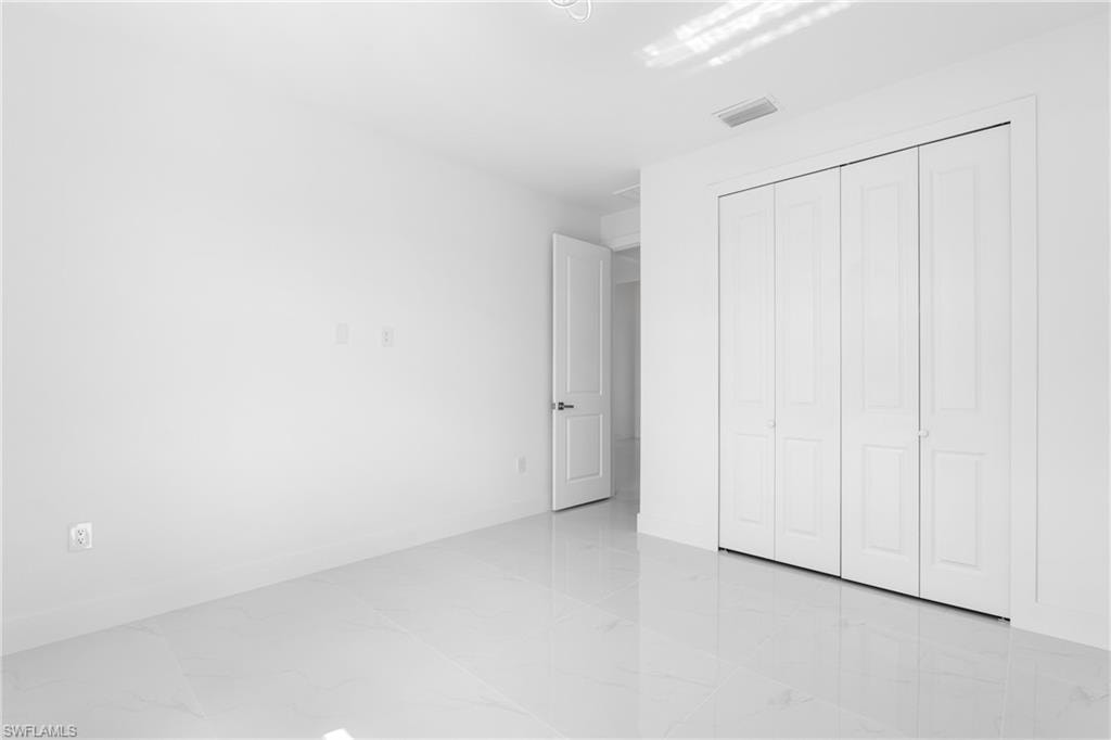 Unfurnished bedroom featuring a closet and light marble finish floors