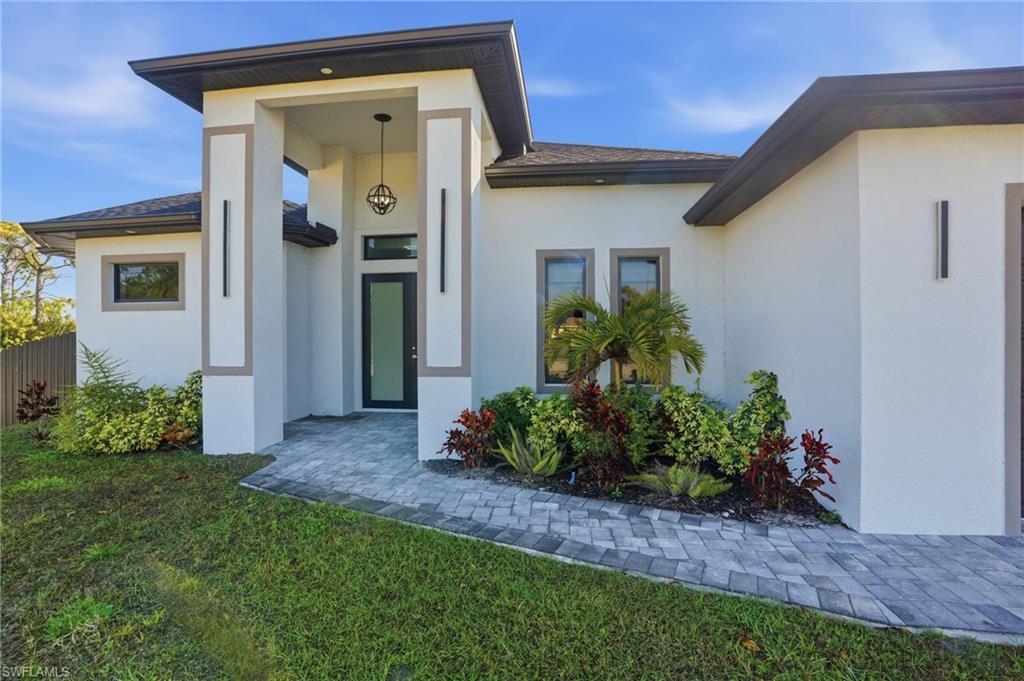 Doorway to property with stucco siding and roof with shingles