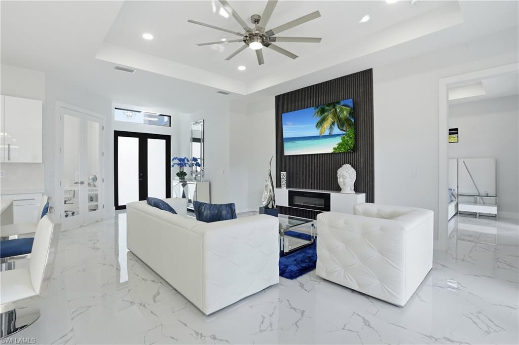 Living room featuring a tray ceiling, recessed lighting, ceiling fan, and french doors