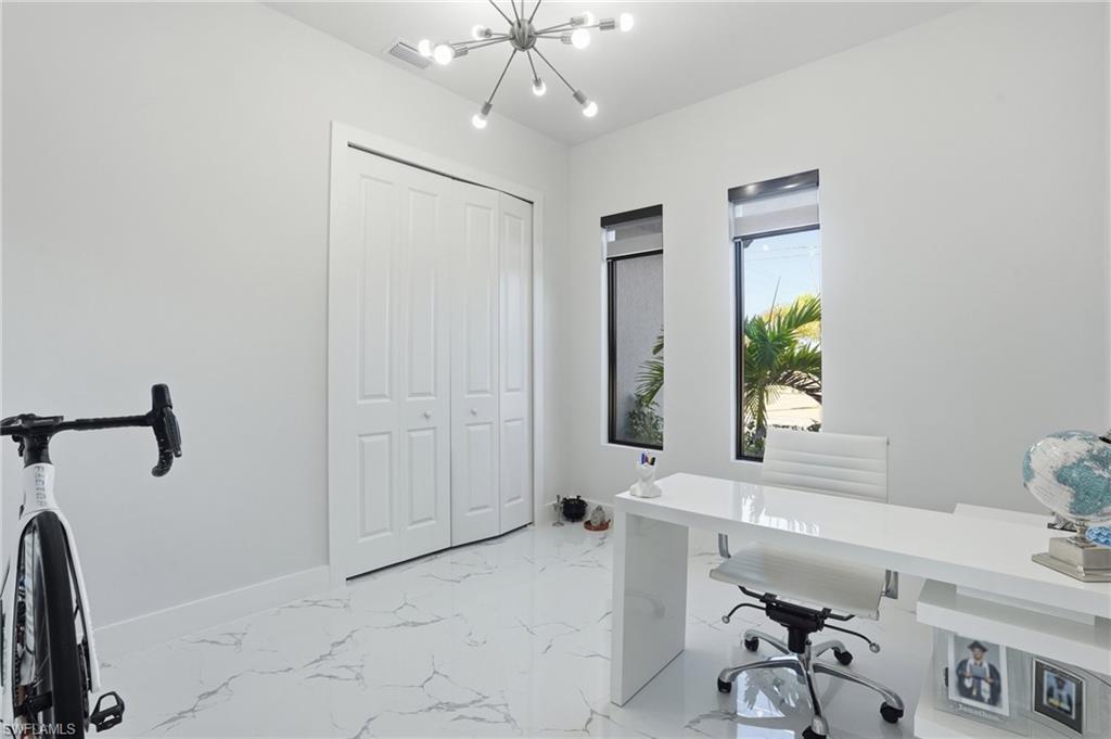 Home office with suspended lighting and light marble finish flooring