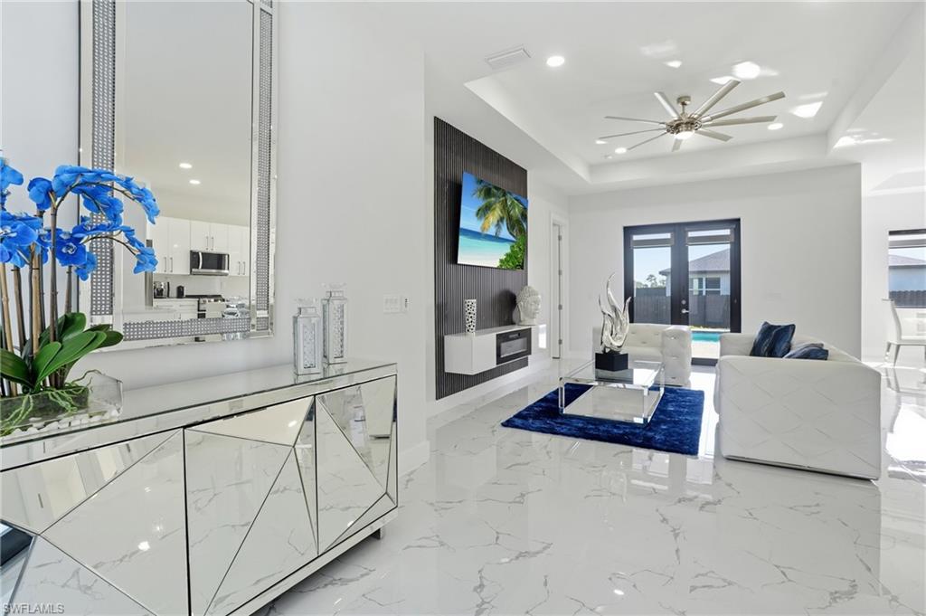 Living room featuring recessed lighting, french doors, light marble finish floors, and a tray ceiling
