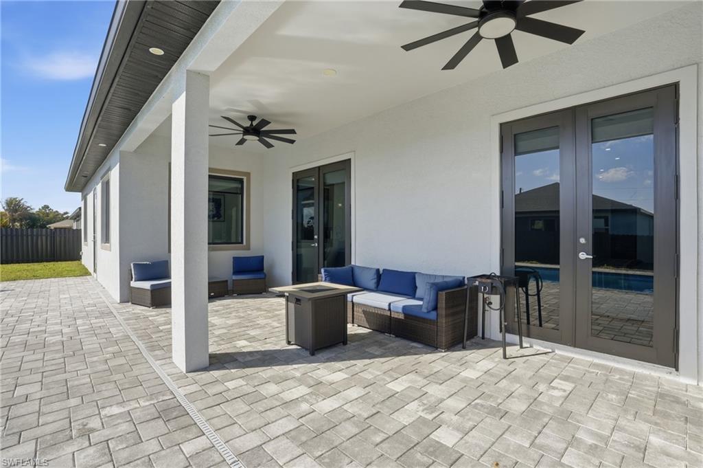 View of patio featuring an outdoor living space with a fire pit, french doors, and a ceiling fan