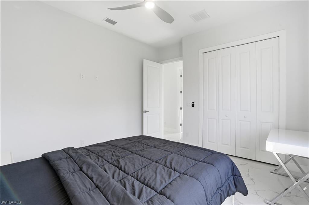 Bedroom featuring light marble finish floors, a closet, and ceiling fan