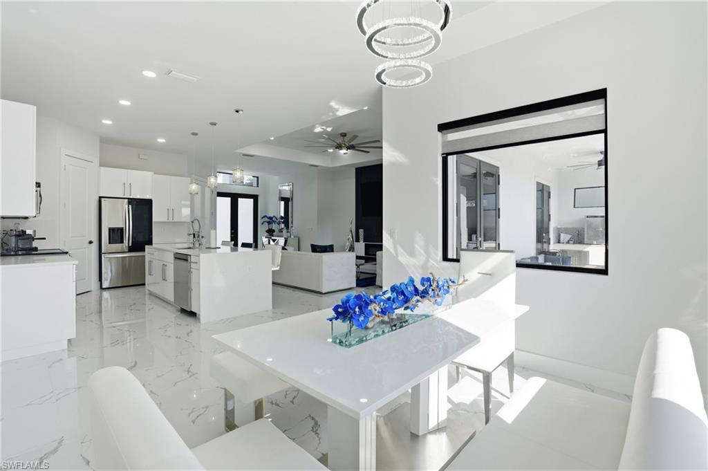 Dining area with a ceiling fan, hanging lights, and light marble finish floors