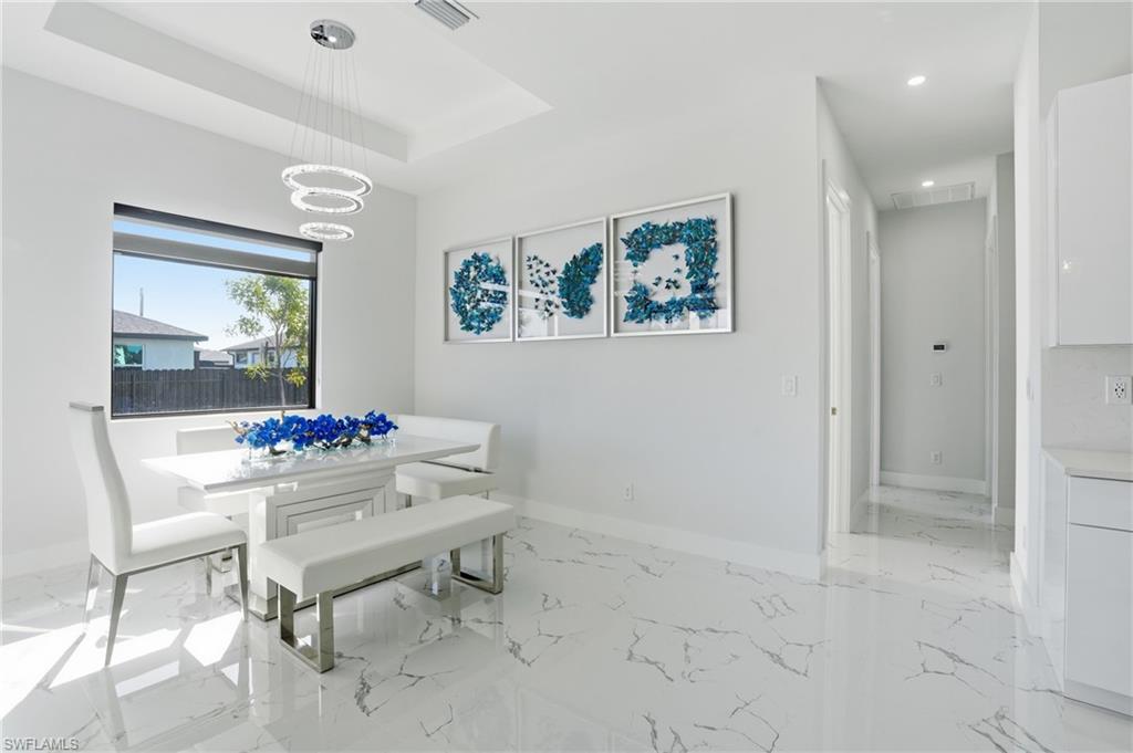 Dining room featuring light marble finish flooring and a raised ceiling