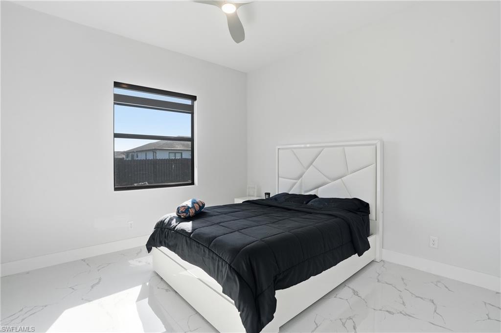 Bedroom with a ceiling fan and light marble finish floors