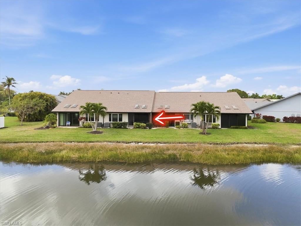 Rear view of property featuring a water view and a lawn