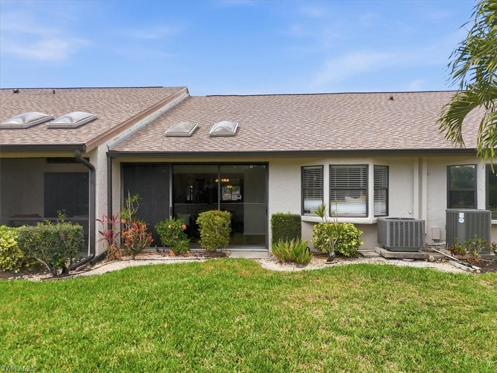 View of front of home featuring a shingled roof, stucco siding, and a front yard