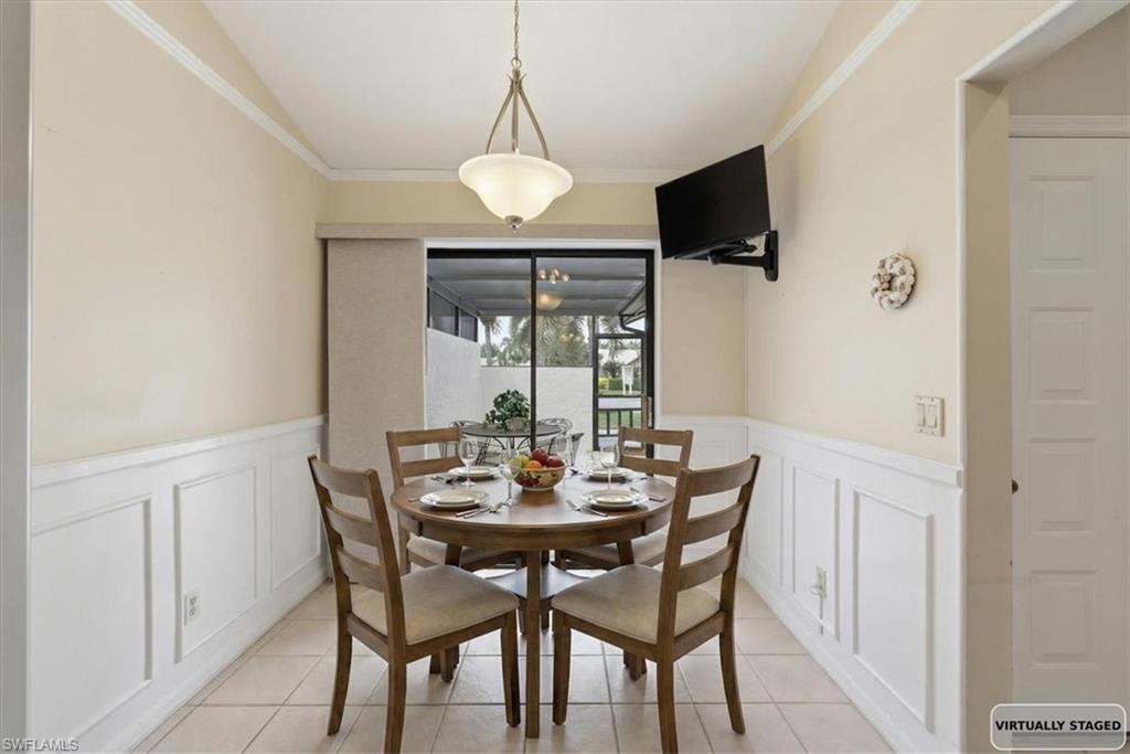 Dining room with ornamental molding, wainscoting, and a decorative wall
