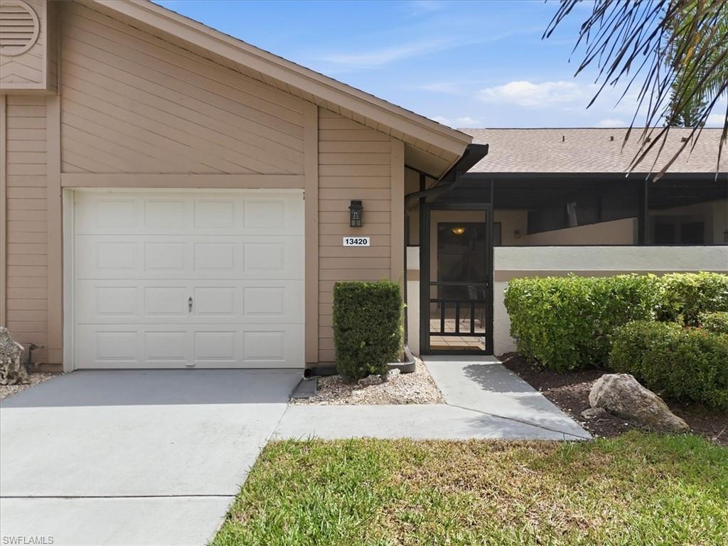 View of exterior entry with driveway, a sunroom, an attached garage, and roof with shingles