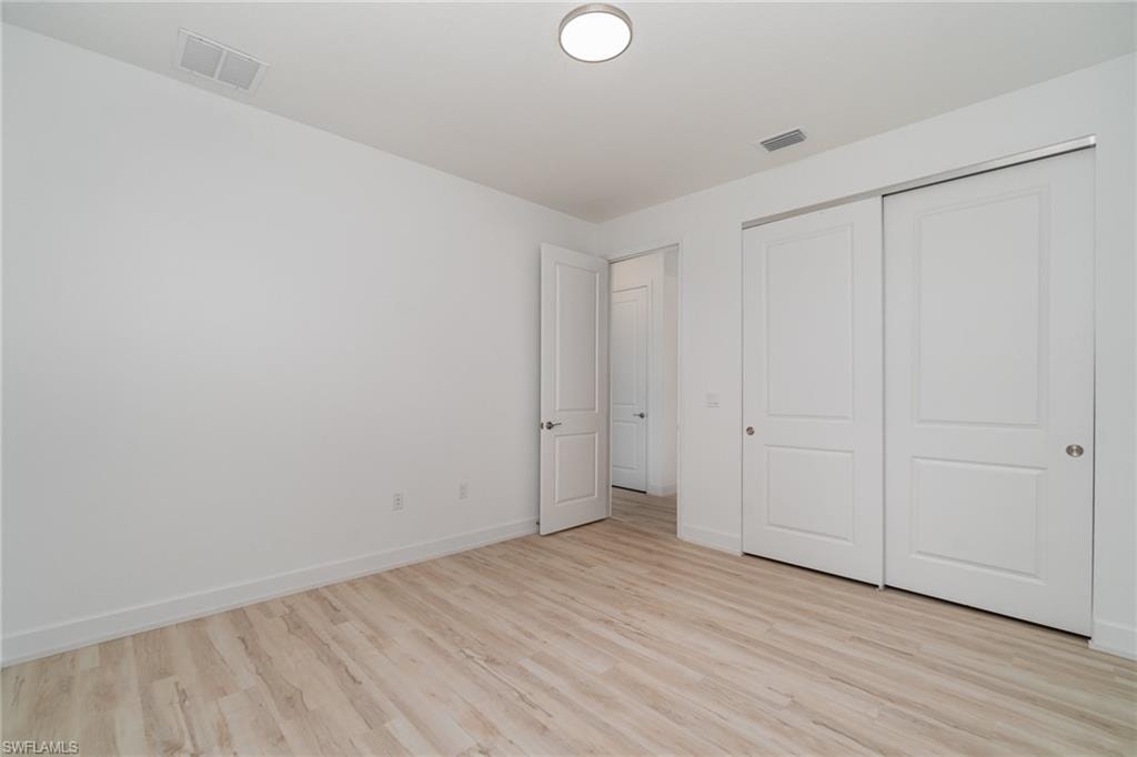 Unfurnished bedroom featuring light wood-style flooring and a closet