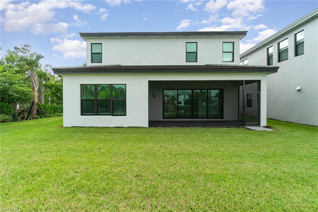 Back of house featuring stucco siding, a lawn, and a sunroom