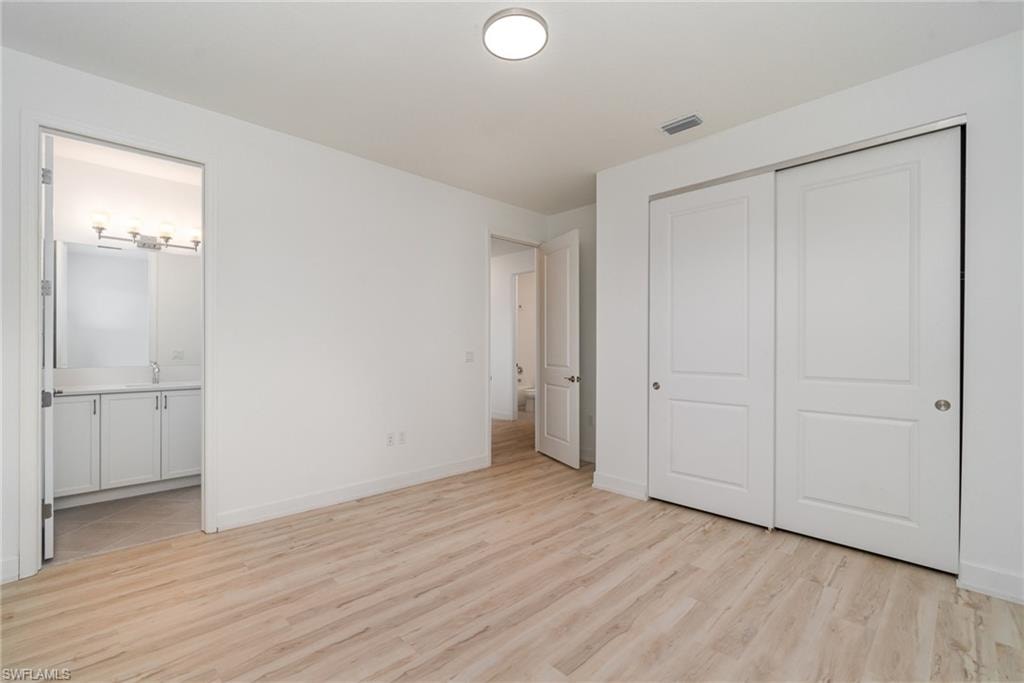 Unfurnished bedroom featuring light wood-style floors and a closet