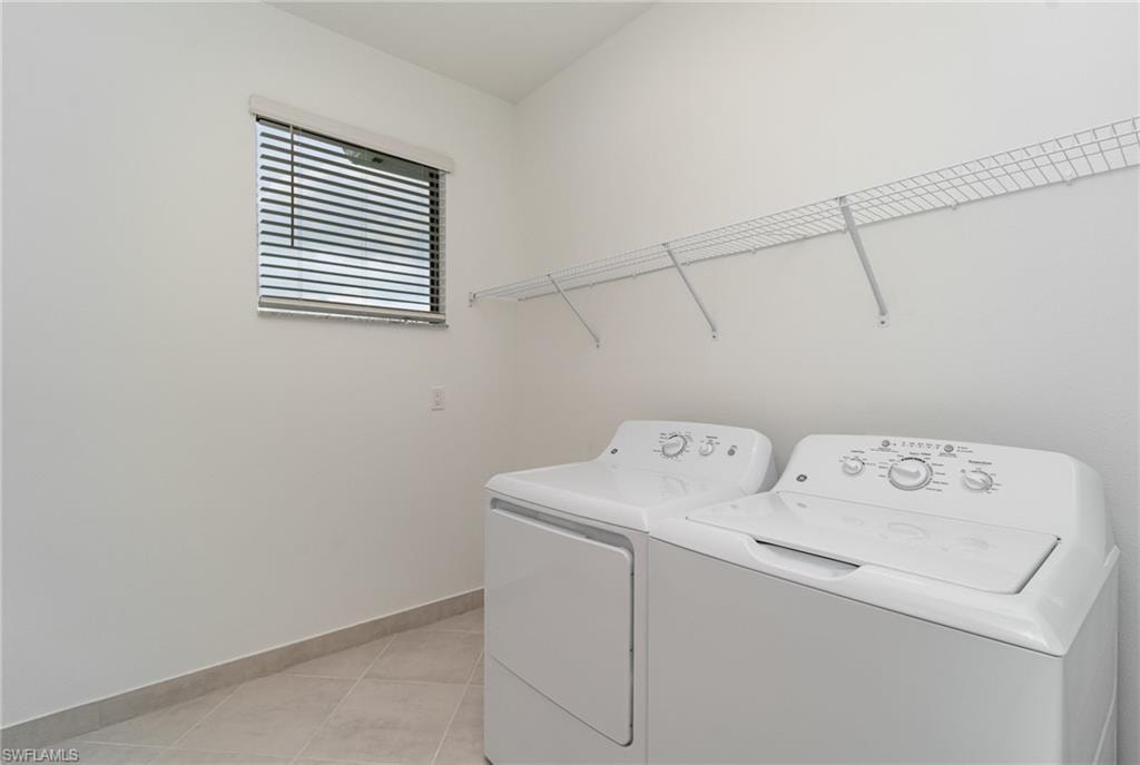 Laundry room featuring washing machine and dryer and light tile patterned floors