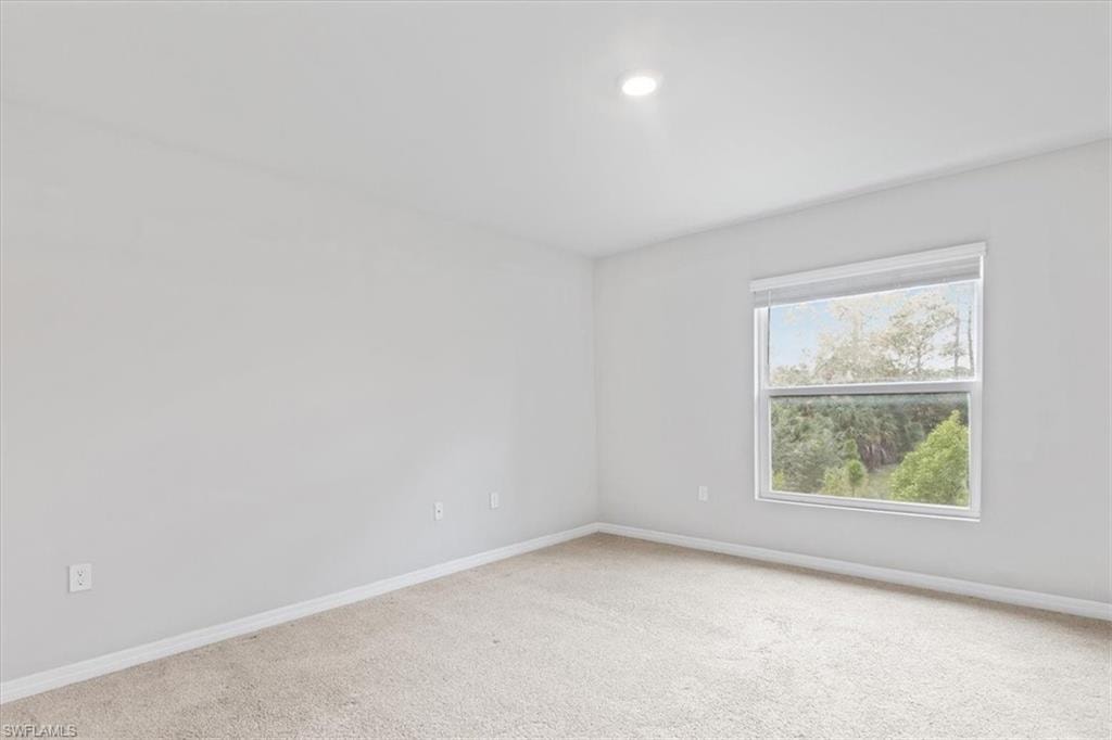 Spare room featuring carpet flooring and baseboards