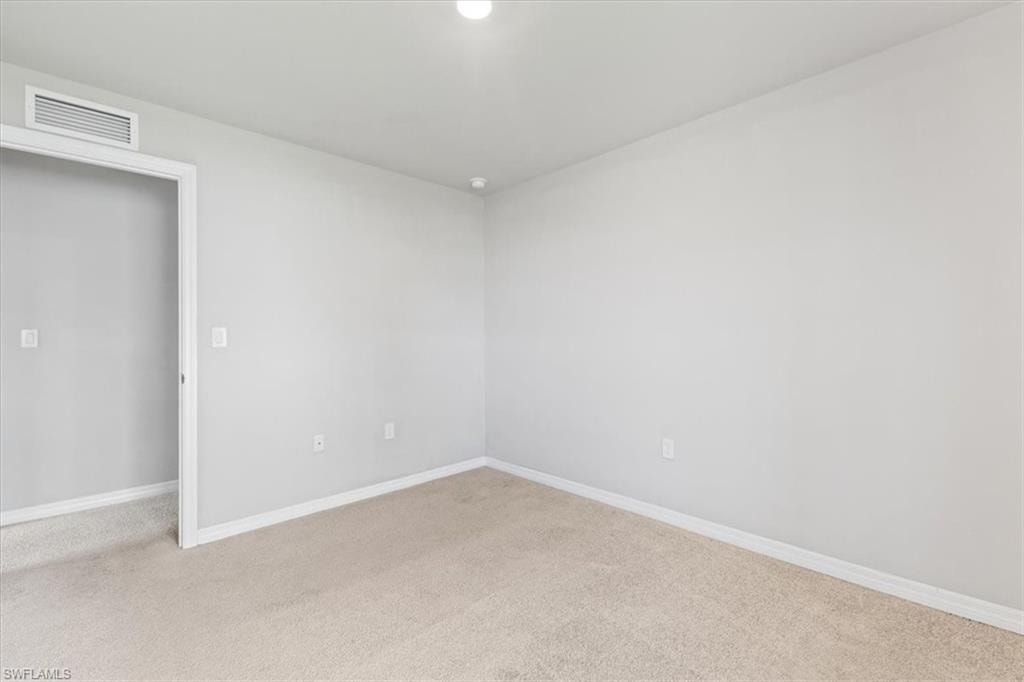 Unfurnished room featuring baseboards and light carpet