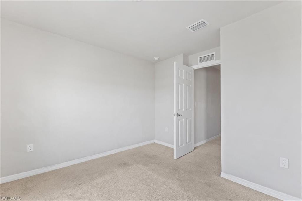 Empty room with light colored carpet and baseboards