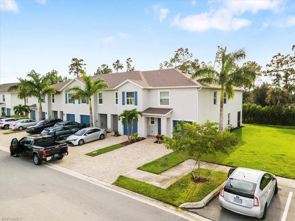 View of front of house featuring stucco siding, a residential view, a shingled roof, and uncovered parking
