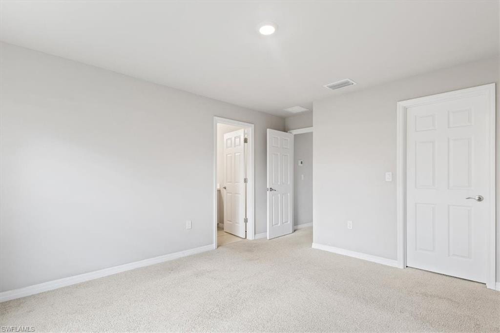 Unfurnished bedroom featuring light colored carpet and baseboards