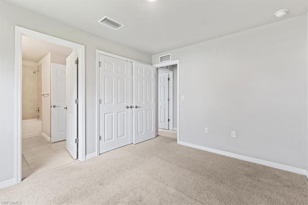 Unfurnished bedroom featuring light colored carpet, a closet, and connected bathroom