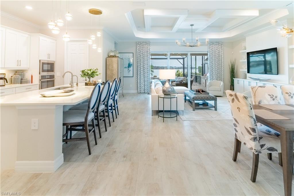 Kitchen with decorative light fixtures, white cabinetry, a breakfast bar area, ornamental molding, and stainless steel appliances