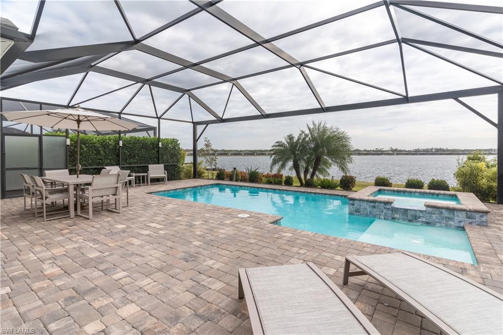 View of swimming pool with a water view, an in ground hot tub, a patio area, and glass enclosure