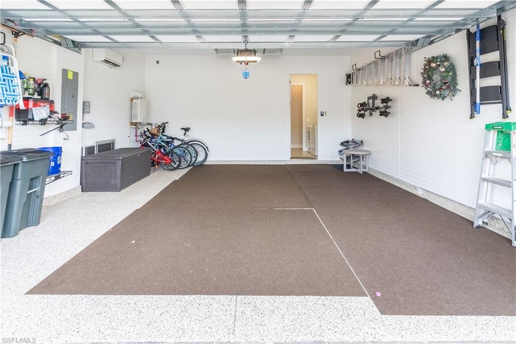 Garage with a garage door opener, electric panel, and an AC wall unit
