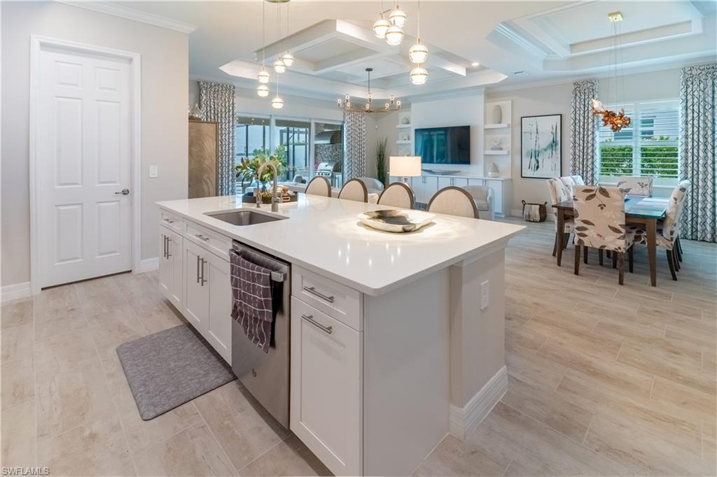 Kitchen featuring pendant lighting, a kitchen island with sink, stainless steel dishwasher, and white cabinets