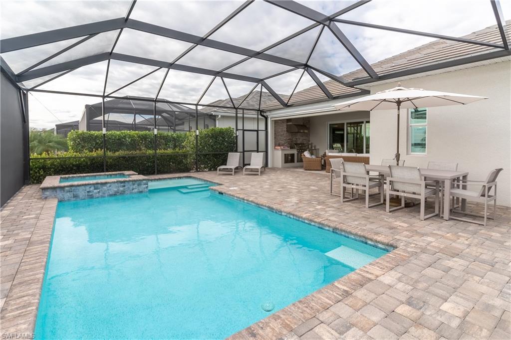 View of swimming pool featuring an in ground hot tub, a patio, and glass enclosure