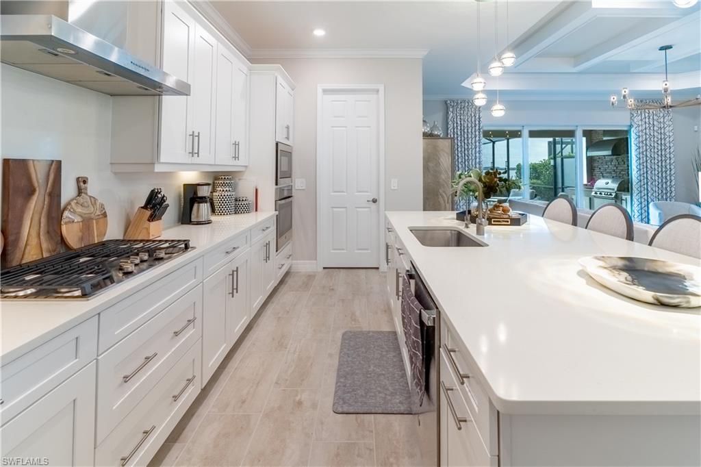 Kitchen with decorative light fixtures, ventilation hood, sink, and white cabinets