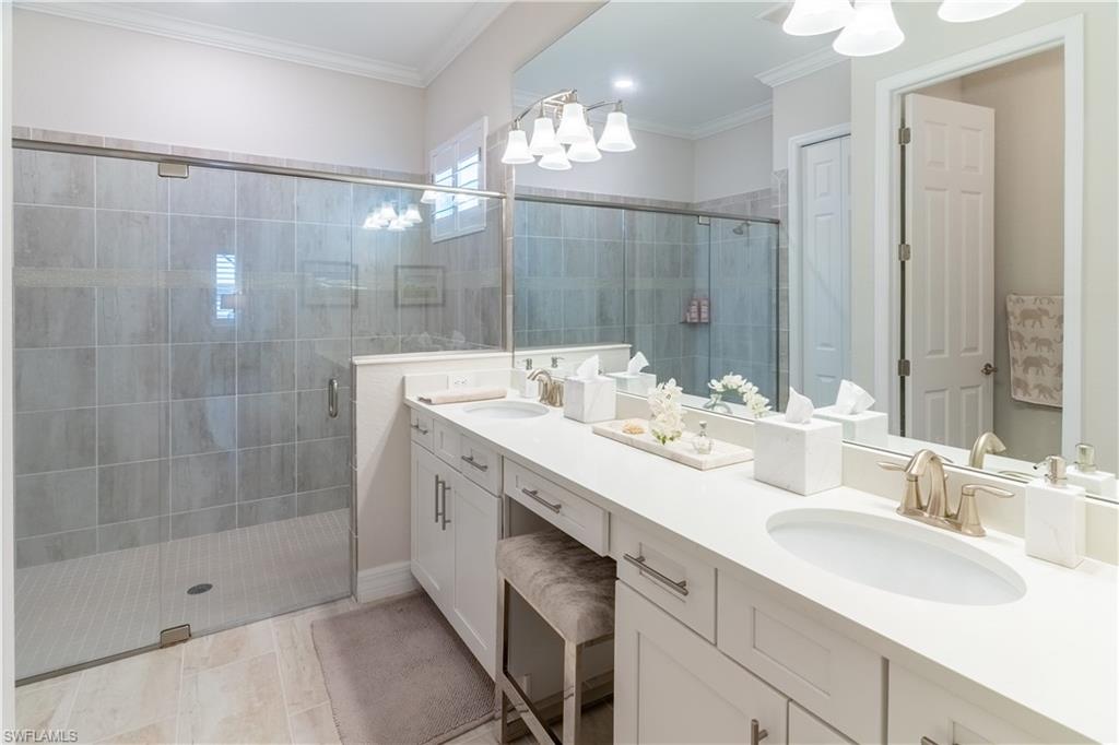 Bathroom featuring vanity, a shower with door, ornamental molding, and tile patterned floors