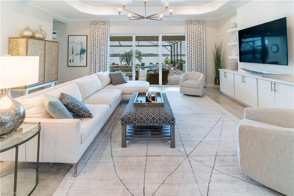Living room with crown molding, a tray ceiling, light hardwood / wood-style floors, and a chandelier