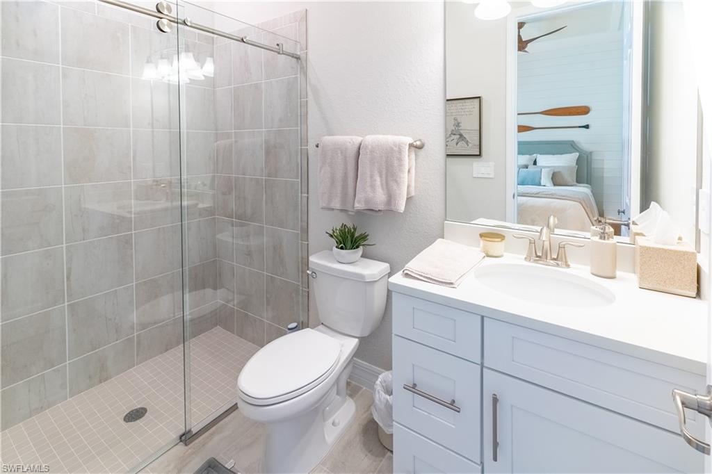 Bathroom featuring vanity, a shower with shower door, and toilet