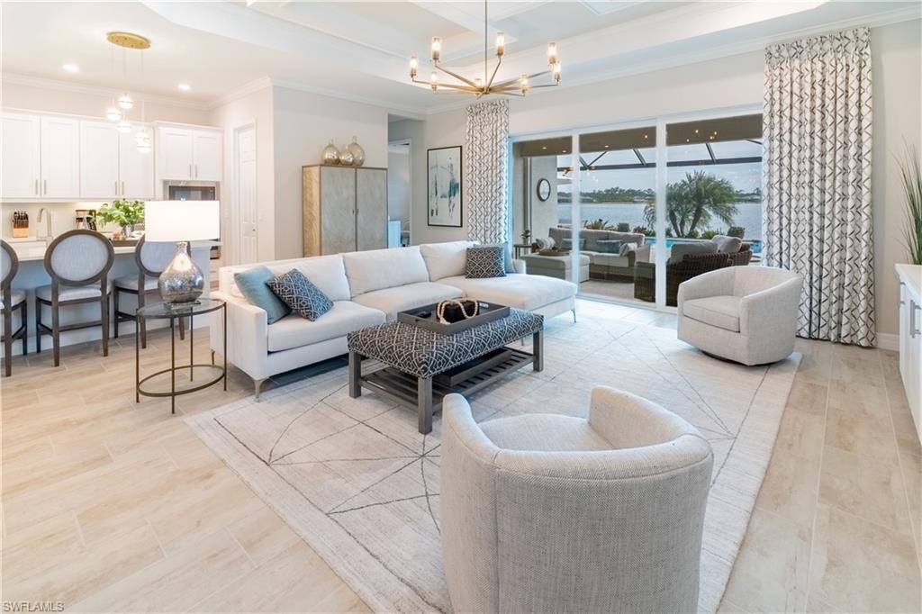 Living room with an inviting chandelier, crown molding, and a raised ceiling