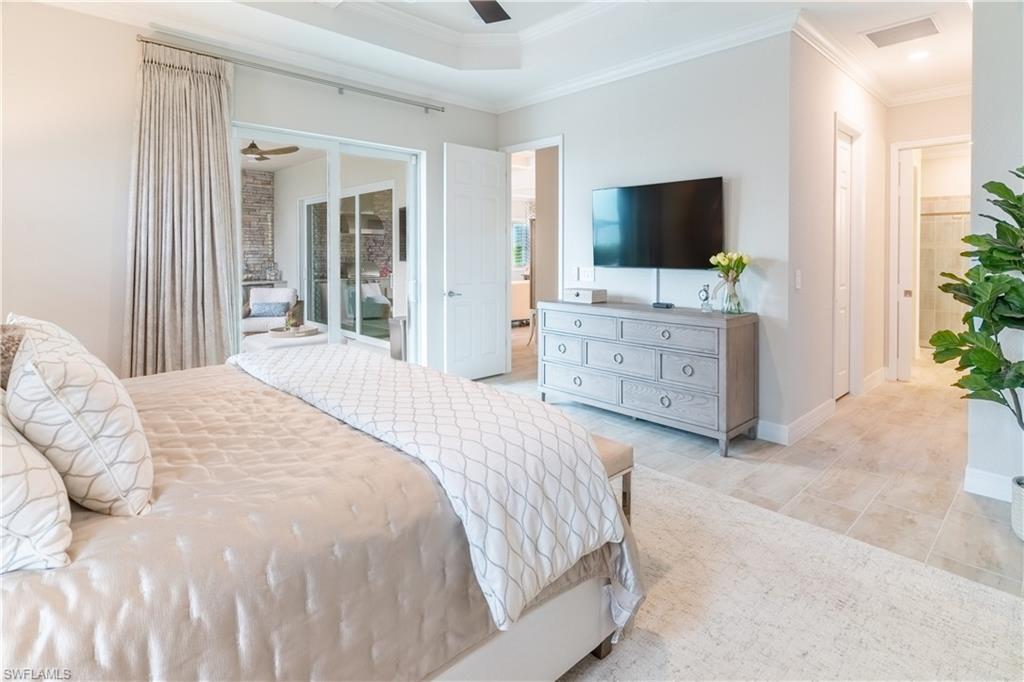 Tiled bedroom with crown molding, ceiling fan, and a tray ceiling