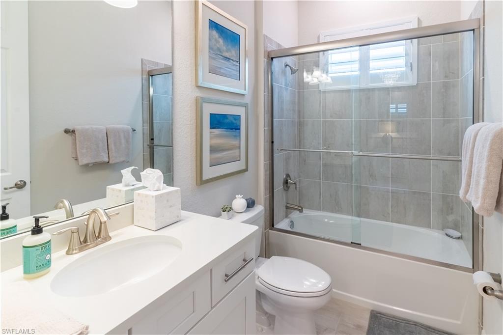 Full bathroom featuring vanity, tile patterned floors, shower / bath combination with glass door, and toilet