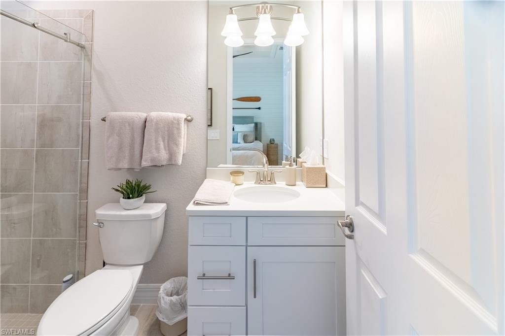 Bathroom with an inviting chandelier, vanity, toilet, and an enclosed shower