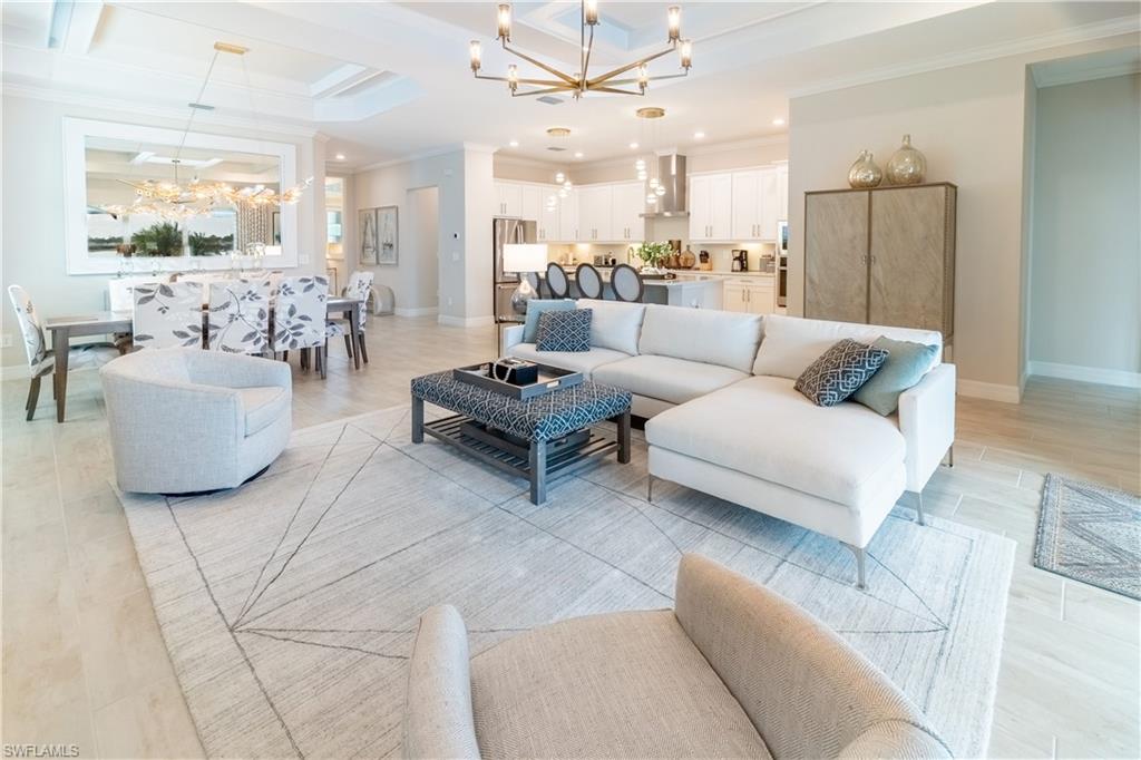 Living room featuring an inviting chandelier, crown molding, light hardwood / wood-style flooring, and a raised ceiling