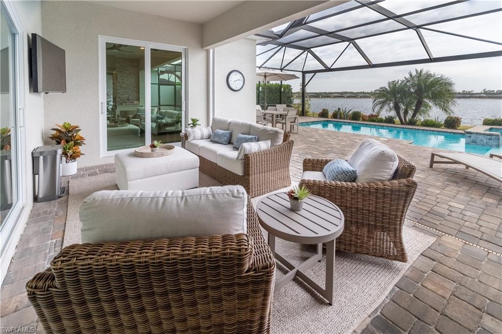 View of patio with an outdoor living space, a water view, and glass enclosure
