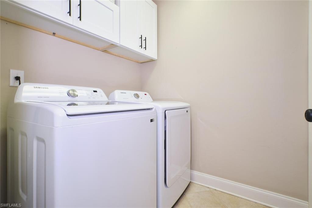Laundry area with cabinet space, separate washer and dryer, and light tile patterned floors