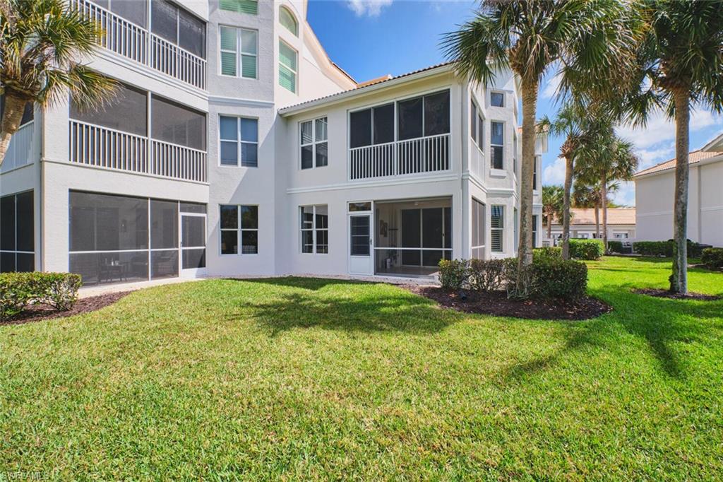 Rear view of property featuring a sunroom, stucco siding, a yard, and a balcony
